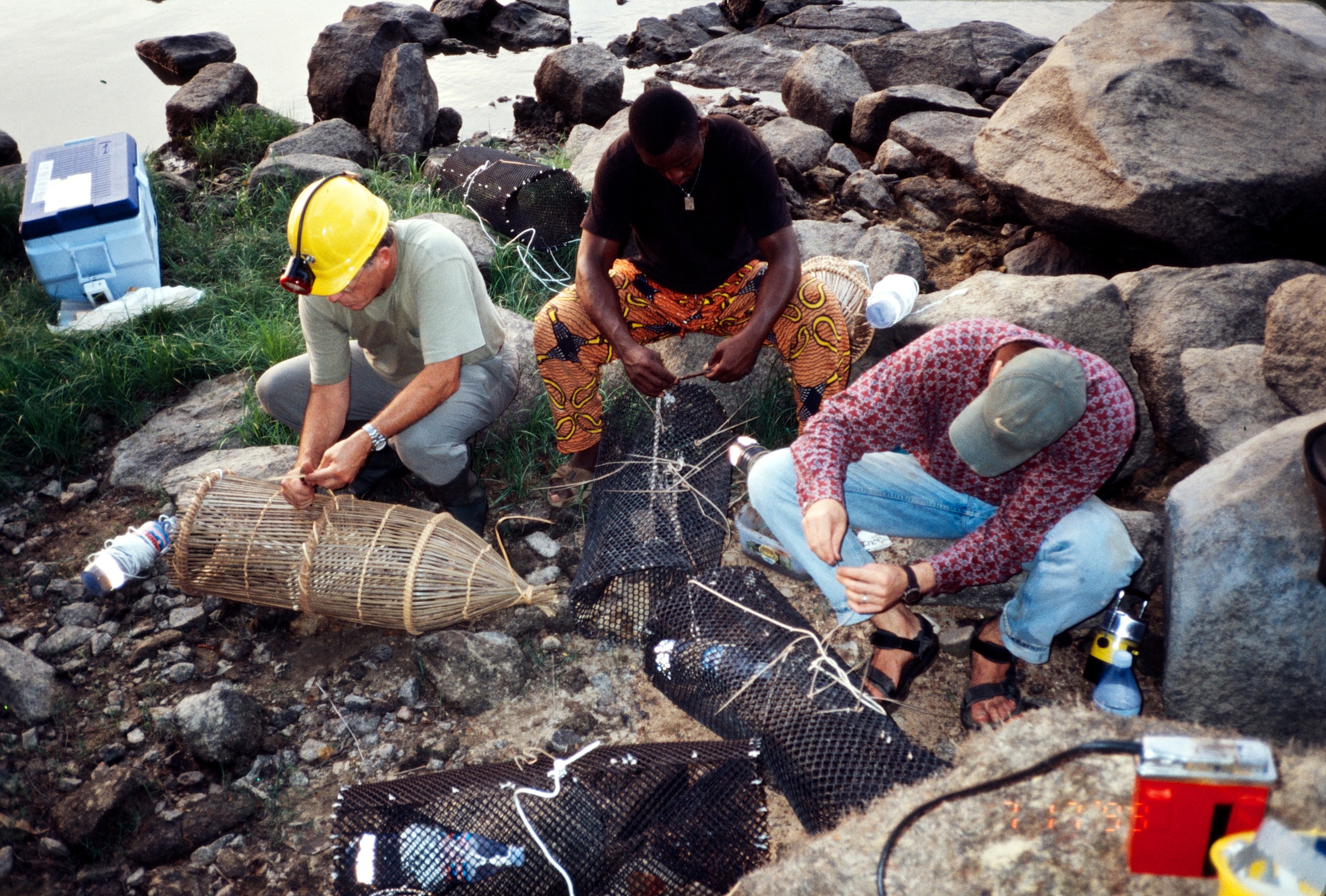 Baiting traditional Gabonese (left) and Hopkins-model (right) fish traps with earthworms before an evening of fishing, Ogooué River, Gabon